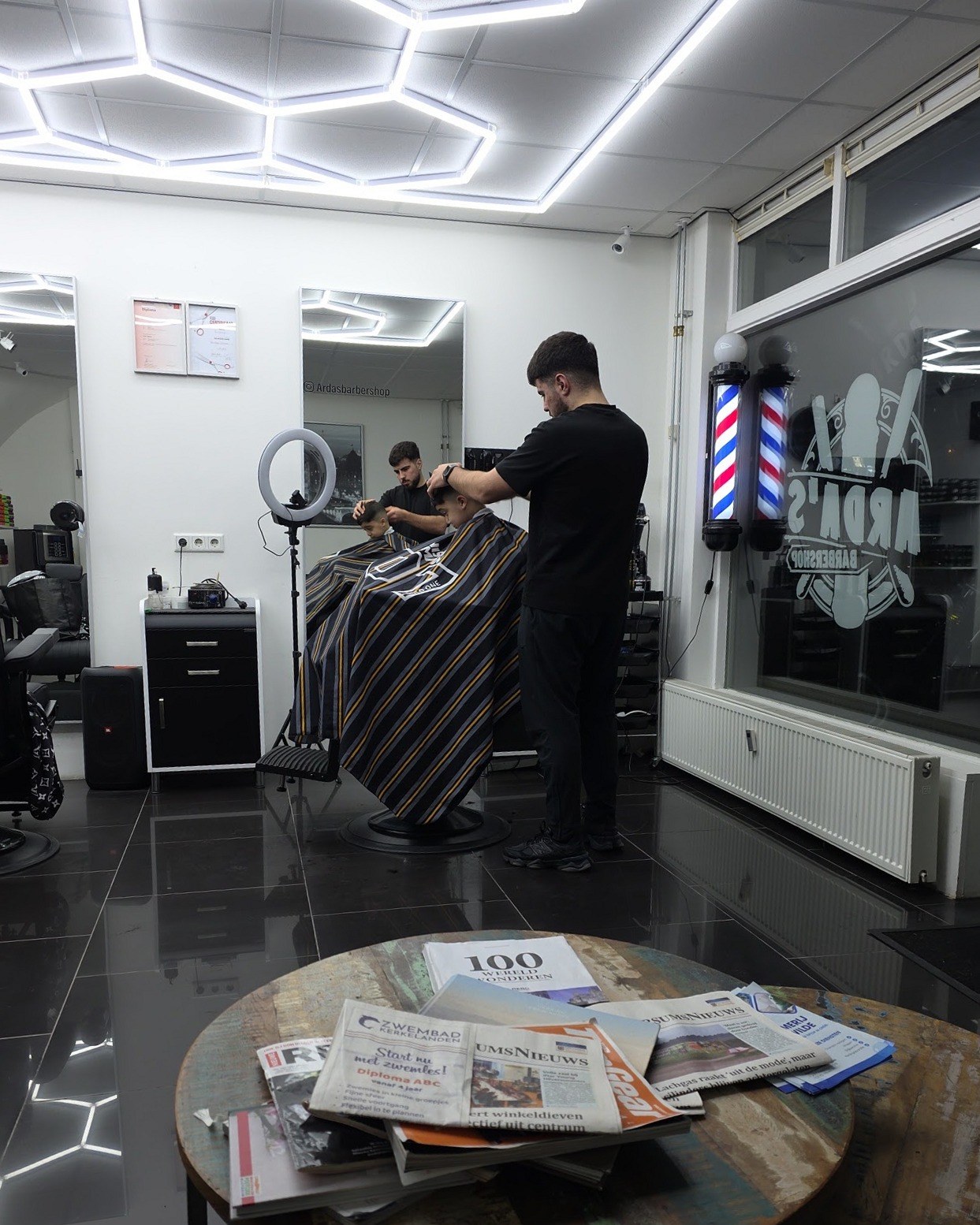 Interieur met zeshoekige ledverlichting, barberpalen en een barbier aan het werk