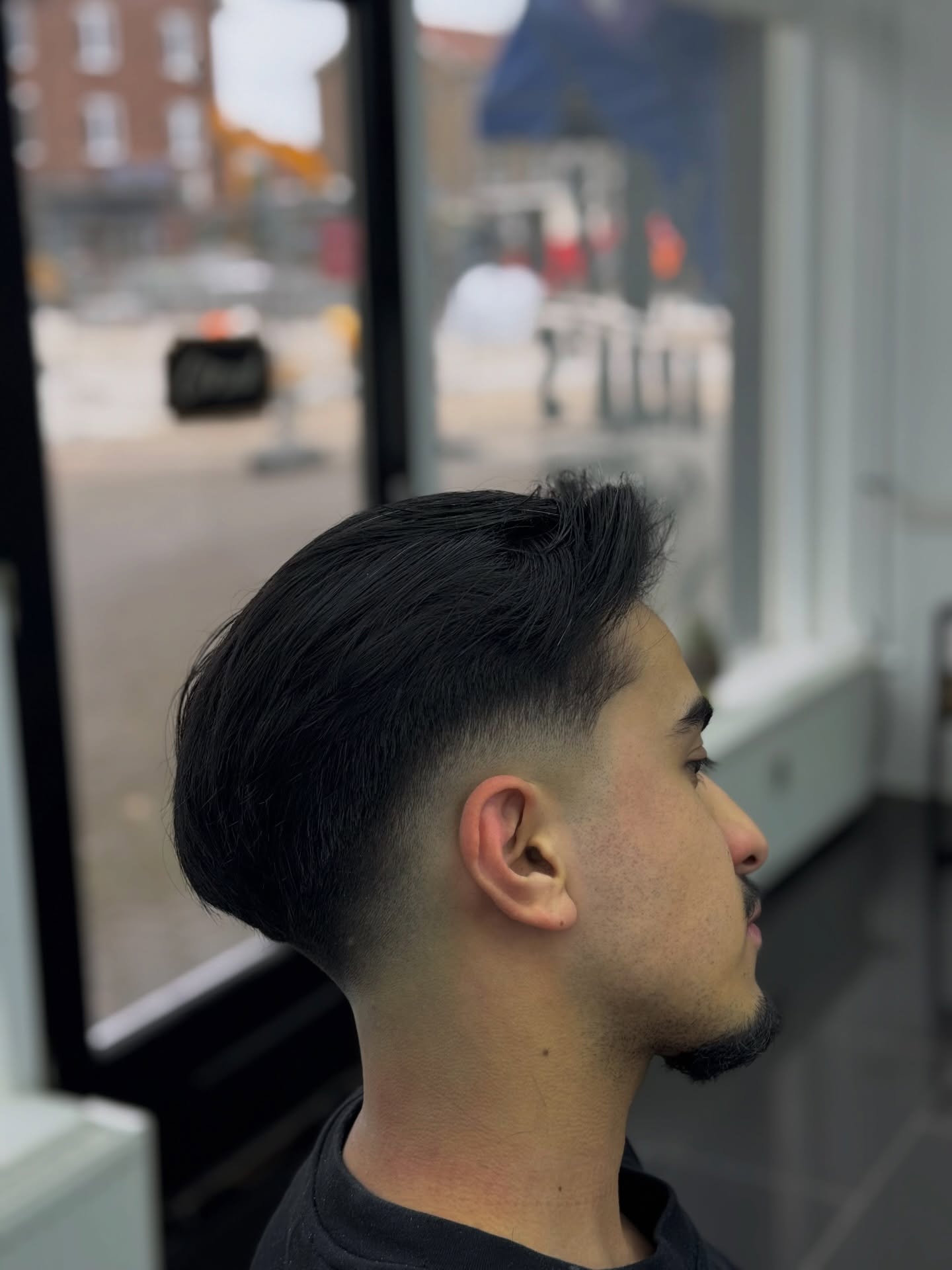 Taper fade met volume bovenop, zijaanzicht bij het raam