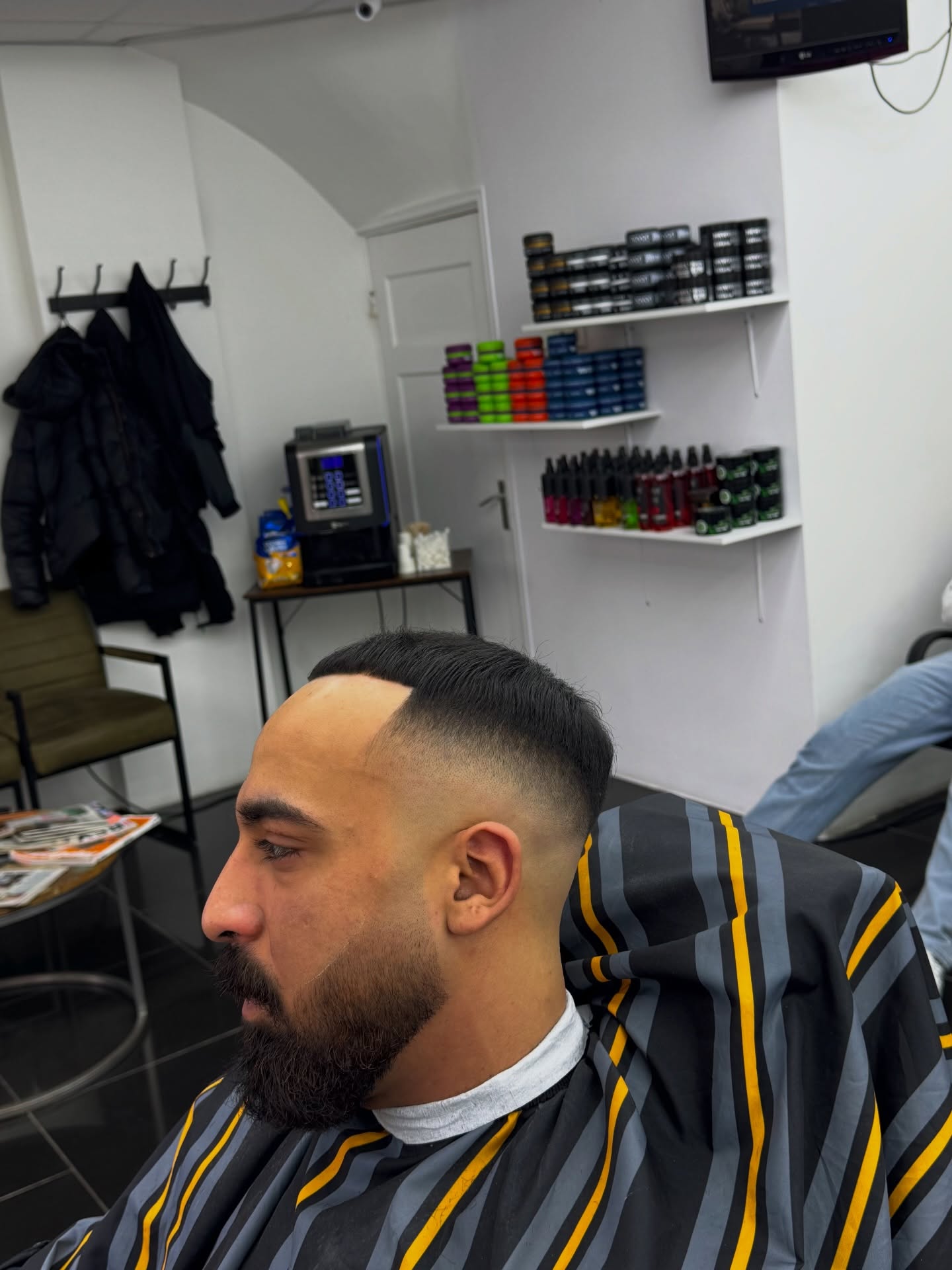 Klant met een fade en een strak getrimde baard in de stoel